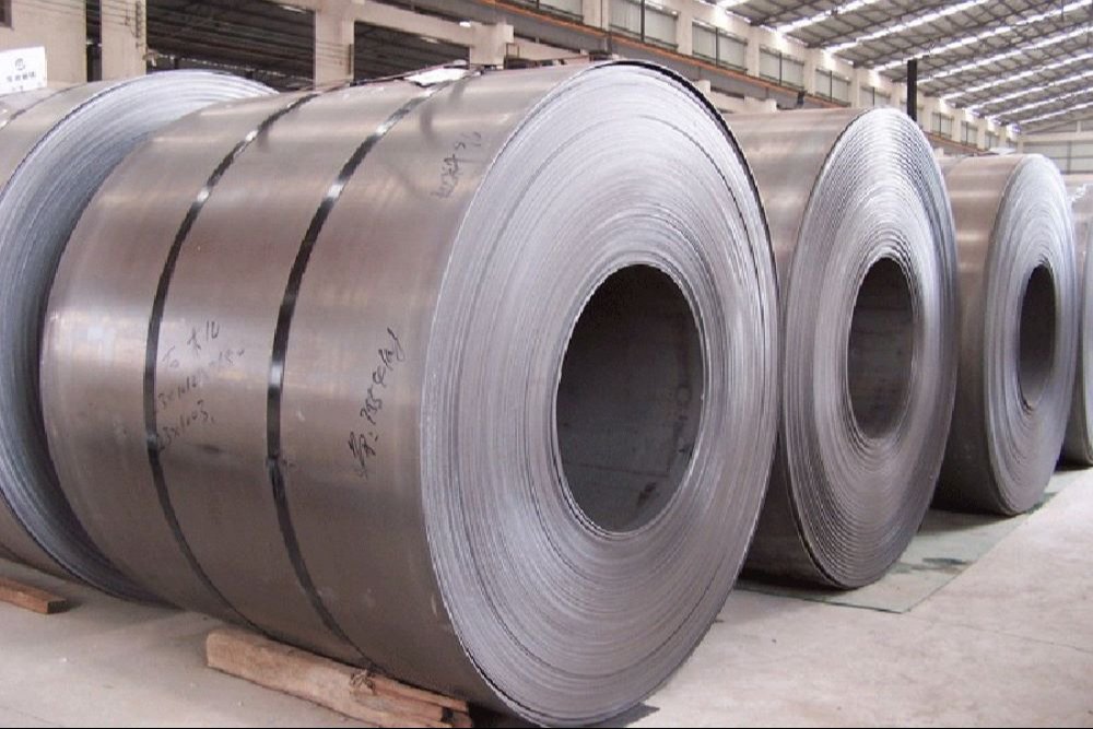 Large hot-rolled steel coils stacked in industrial warehouse — premium coils in all grades and thicknesses, sourced directly from global steel mills